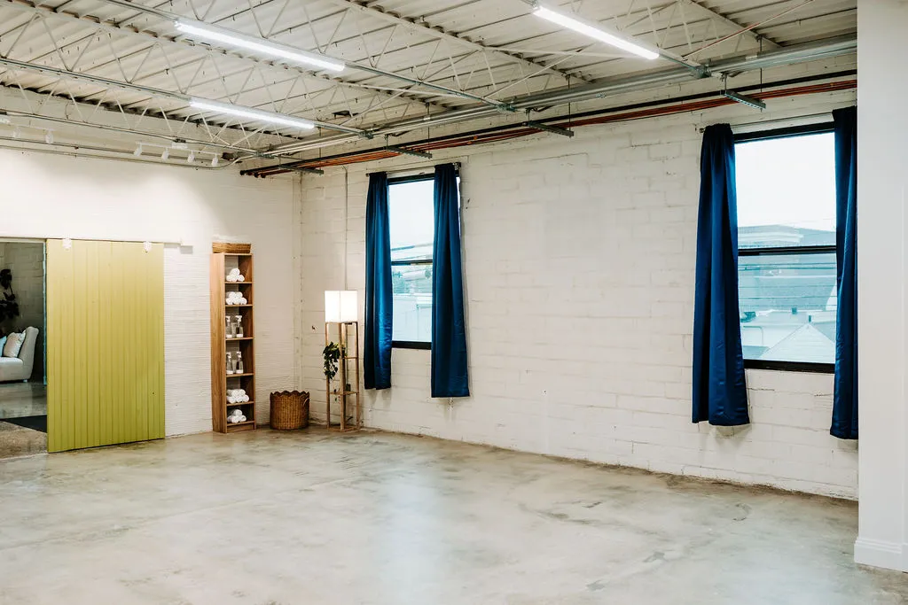 The bright main studio room with navy curtains and a green sliding door