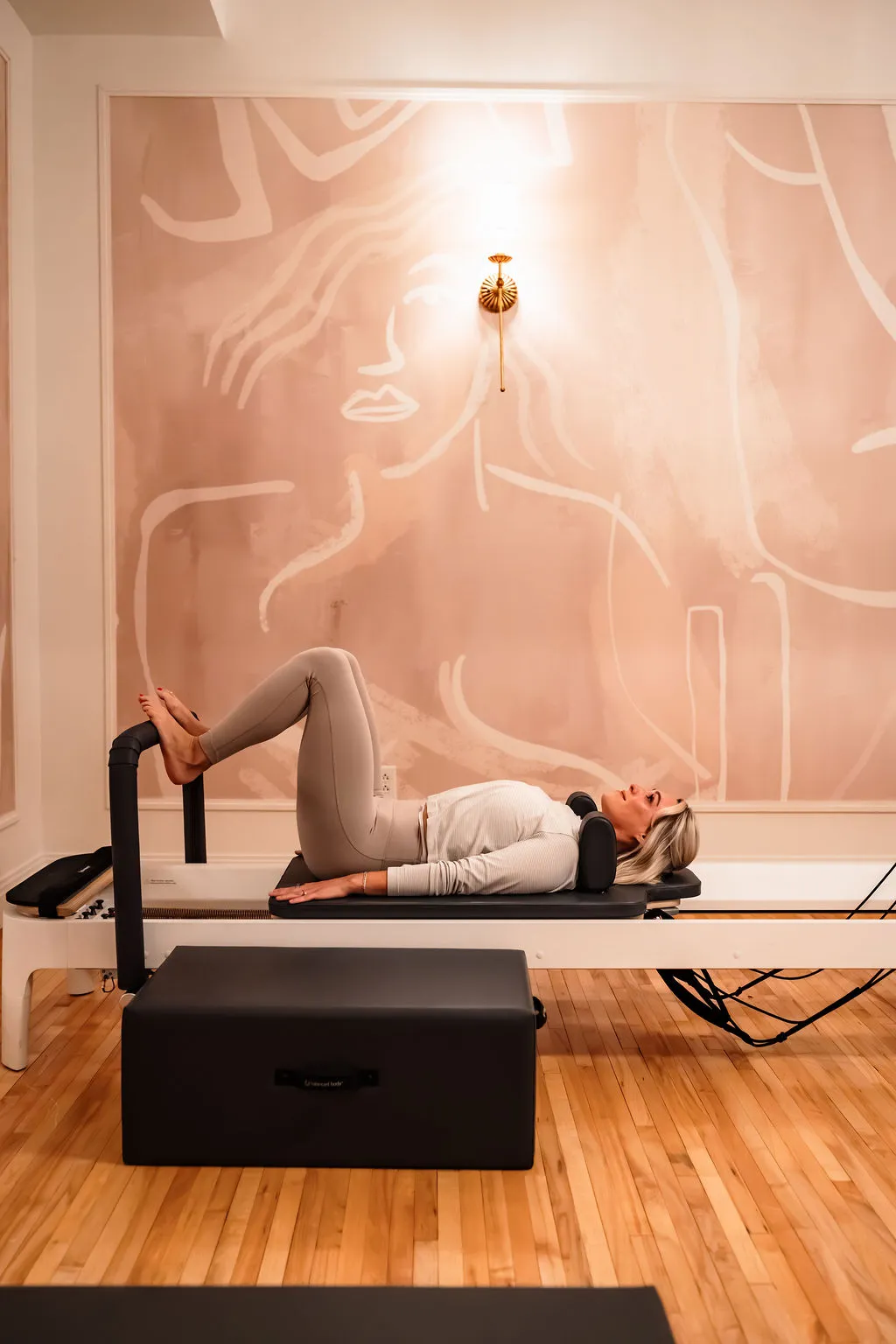 A client working on a reformer in the pink reformer room