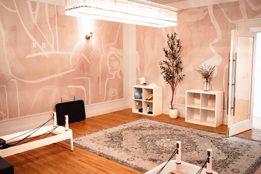 The pink reformer room with two reformers and a vintage rug